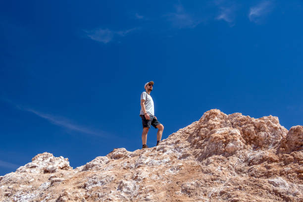 Young casual caucasian man on the top of the cliff at Valle de la Luna (Moon valley), Chile Young casual caucasian confident man on the top of the cliff at moon like landscape of Valle de la Luna (Moon valley), Chile. Wanderlust vocation outdoor travel lifestyle chile tourist stock pictures, royalty-free photos & images