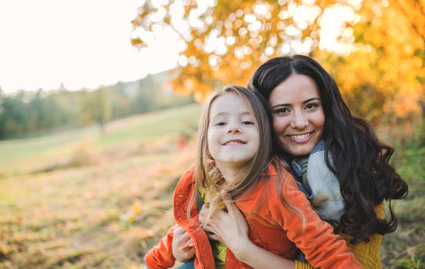 un ritratto di giovane madre con una bambina piccola nella natura autunnale al tramonto. - autumn women leaf scarf foto e immagini stock