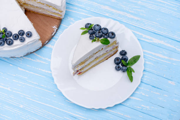 istock Appetizing cheesecake cake biscuit pillow decorated white cream blueberries and mint stands on wooden blue rustic table 1173345735