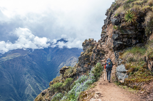 Young hiker man trekking with backpack in Peruvian mountains. Active outdoor vocation getaway hiking in Peru