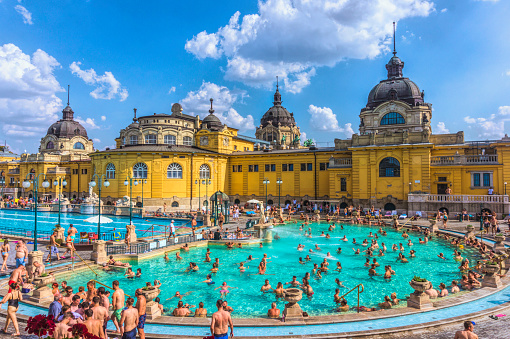 Budapest, Hungary - August 30, 2019: Famous Secheni Thermal Pools in Budapest, Hungary. Having fun and bathing people. Wellness complex of public therapeutic pools and saunas for water treatments. Budapest ancient tourist attraction