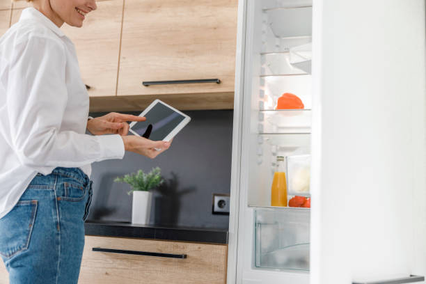 istock Pretty lady is managing fridge with tablet 1173353044