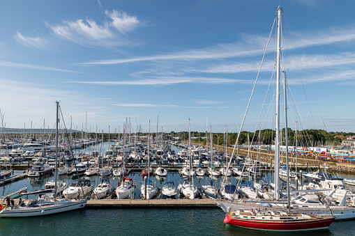 Lymington, UK - September 8, 2019: A large number of boats moored in Lymington Marina in Hampshire. People are using smaller boats on the channels.