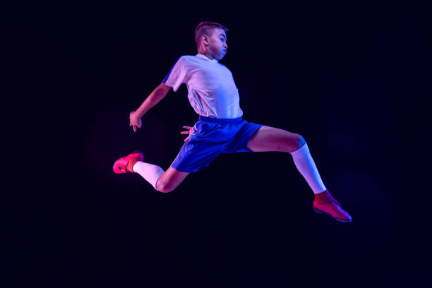 istock Young boy as a soccer or football player on dark studio background 1173355905