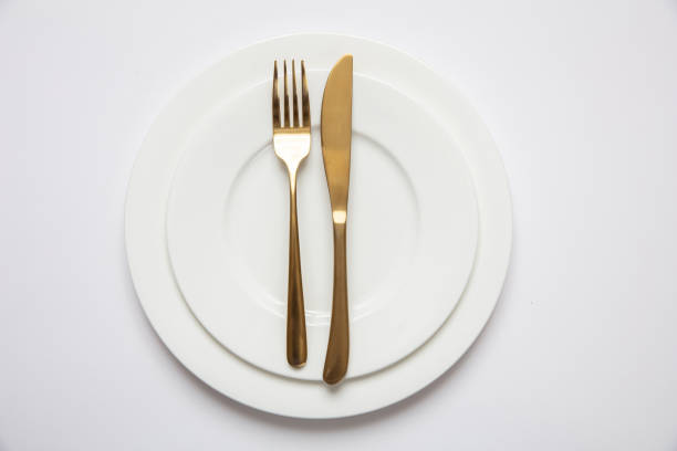 tabelleneinstellung, formal. goldbesteck auf weißem tellersatz, weißem hintergrund - nobody table knife food dinner stock-fotos und bilder