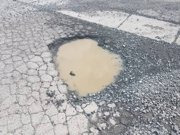 istock mud and water puddle in black cracked asphalt 1173358498