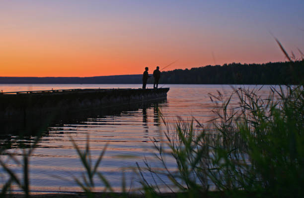 740+ A Silhouette Of Two Men Fishing At Sunset Stock Photos
