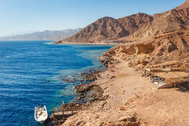 Sunny resort beach at the coast shore of Red Sea in Dahab, Sinai, Egypt, Asia in summer hot. Famous tourist destination Blue Hole near of Sharm el Sheikh. Bright sunny light