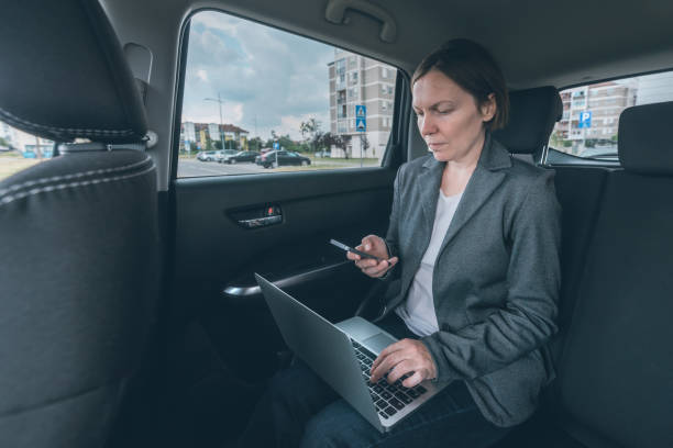 istock Businesswoman using mobile phone and laptop computer in car 1173361668