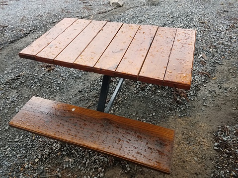 wet brown wood table on grey pebbles or rock gravel