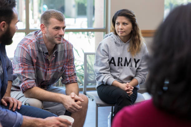 Vulnerable veterans talks during therapy session Mid adult male veterans discusses war experiences during a support group meeting for veterans. war veteran stock pictures, royalty-free photos & images