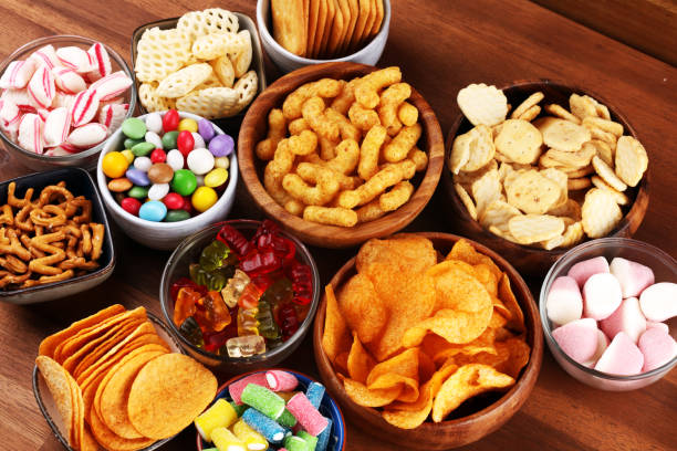istock Salty snacks. Pretzels, chips, crackers and candy sweets on table 1173363751