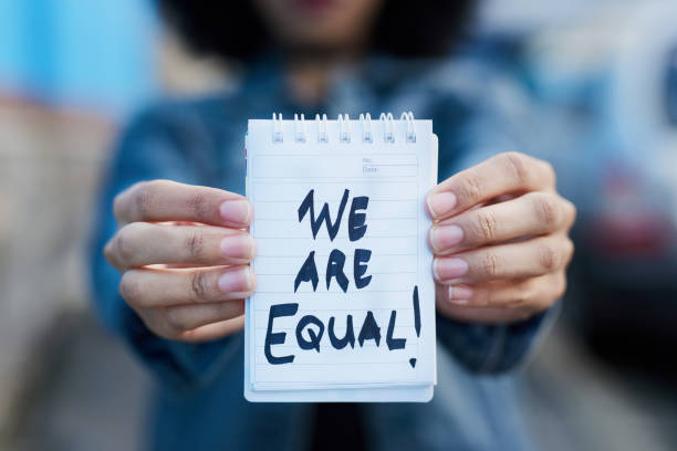 This is a clear statement, not a request Shot of an unrecognizable woman holding a notepad written "WE ARE ALL EQUAL!" in the city gender equality stock pictures, royalty-free photos & images