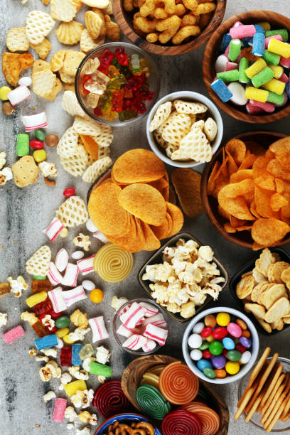 istock Salty snacks. Pretzels, chips, crackers and candy sweets on table 1173366587