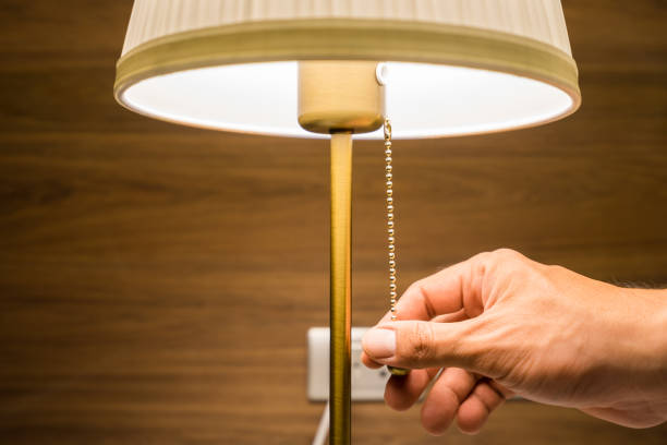 Turning-on the modern bed electrical lamp. Hand of person is turning on or turning off the bedroom 's head lamp which is beautiful luxury-modern designed. Close up and selective focus photo. start button photos stock pictures, royalty-free photos & images