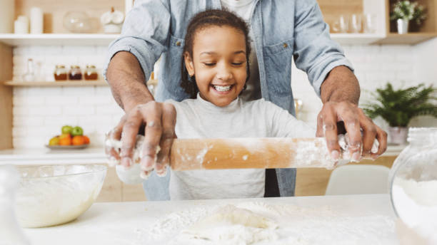 istock Excited black girl rolling dough under dad supervision 1173368212