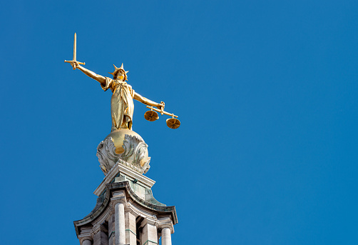 A statue of Lady Justice holding a sword and balancing scales, on top of the Old Bailey, England's criminal court in the City of London, officially called the Central Criminal Court.