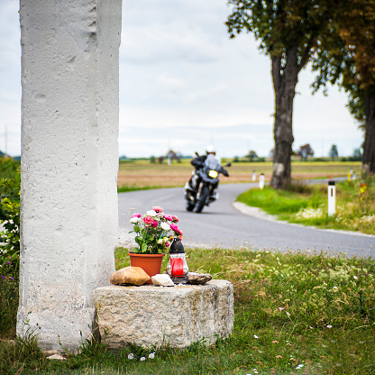 Biker passes a waycross with flowers on the street