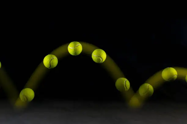Photo of Movement or bounce of tennis ball isolated on black background.