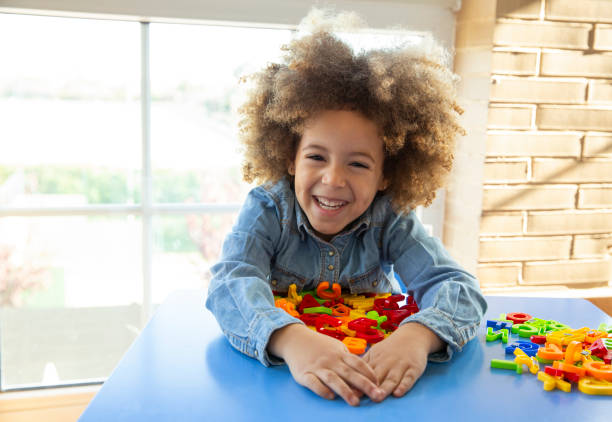 Ethnic kid girl smiling playing with alphabet