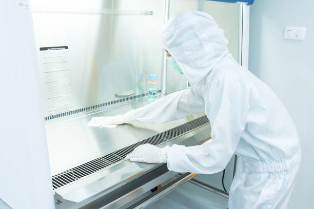 A scientist in sterile coverall gown using alcohol 70% and cleanroom wiper for cleaning Biological Safety Cabinet (BSC) A scientist in sterile coverall gown using alcohol 70% and cleanroom wiper for cleaning Biological Safety Cabinet (BSC). Decontamination before and after using BSC. Cleanroom facility. fume cupboard stock pictures, royalty-free photos & images