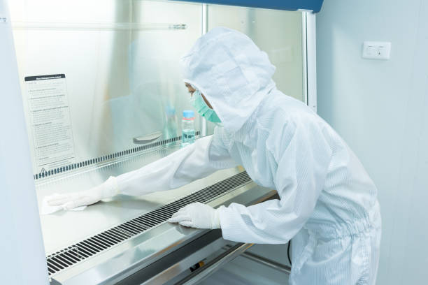 A scientist in sterile coverall gown using alcohol 70% and cleanroom wiper for cleaning Biological Safety Cabinet (BSC) A scientist in sterile coverall gown using alcohol 70% and cleanroom wiper for cleaning Biological Safety Cabinet (BSC). Decontamination before and after using BSC. Cleanroom facility. cleaning cupboard stock pictures, royalty-free photos & images