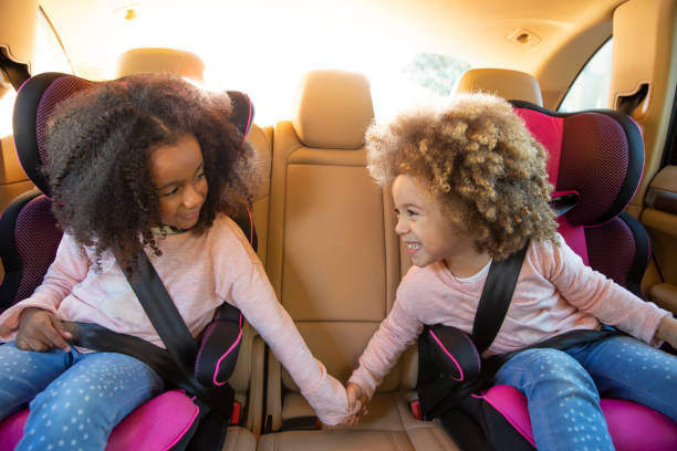 ethnische schwester mädchen auto rücksitz mit gürteln - people child twin smiling stock-fotos und bilder