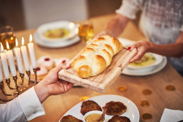 Hanukkah dinner. Family gathered around the table sharing challah Picture of Hanukkah dinner. Family gathered around the table with traditional dishes israel photos stock pictures, royalty-free photos & images