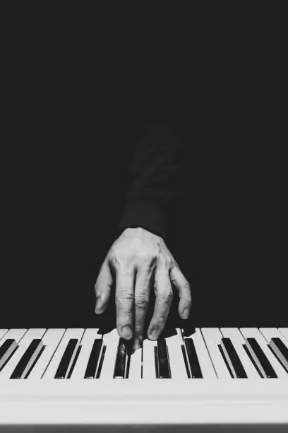 Photo of BW male musician hand playing on piano keys. music background