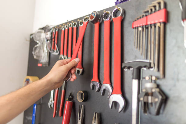 istock Man hand holding wrench. Other tools on the wall. 1173381814