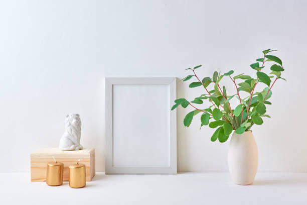 istock Home interior with decor elements. White frame, branches with green leaves in a vase, interior decoration 1173381980