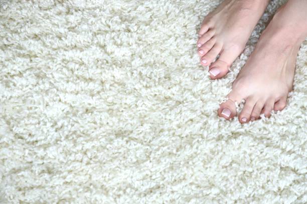 istock Women's feet on a white fluffy carpet 1173382632