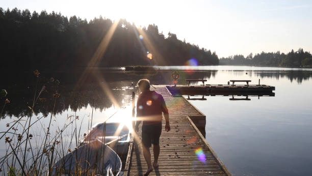 istock Man walks along lakeside pier at sunrise 1173388285