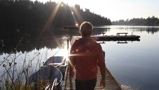 istock Man walks along lakeside pier at sunrise 1173388316