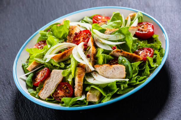 istock Caesar salad  - vegetable salad with roast chicken meat on black stone 1173388319