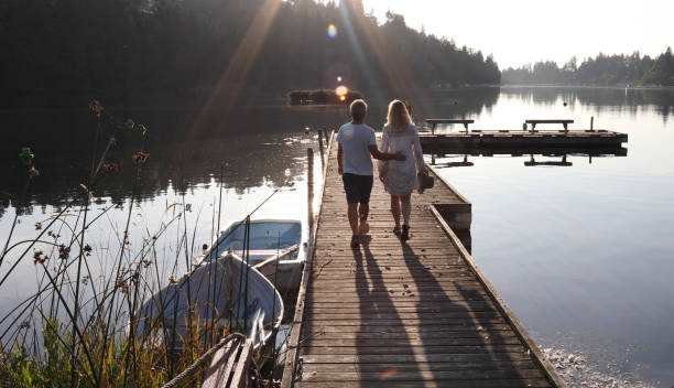 istock Couple walk along lakeside pier at sunrise 1173388468