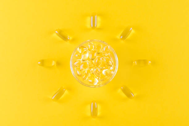 golden omega capsules like sun on yellow background, flat lay golden omega capsules like sun on yellow background, top view vitamin d stock pictures, royalty-free photos & images