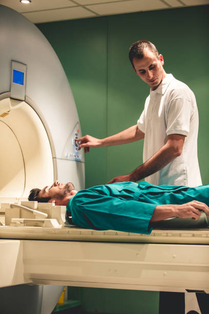 Preparations for an MRI Medical technician preparing patient for an MRI scan. male nurse male healthcare and medicine technician stock pictures, royalty-free photos & images
