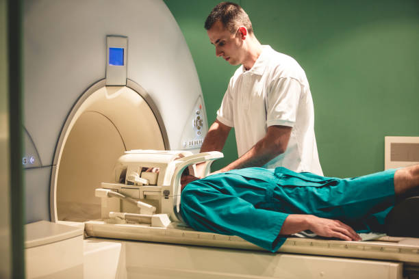 Male technician preparing MRI scan Medical technician is helping patient get ready for an MRI scan male nurse male healthcare and medicine technician stock pictures, royalty-free photos & images