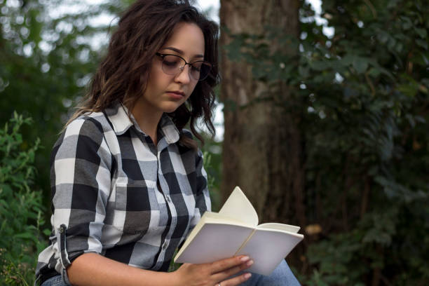 istock girl in the park reads a book 1173400093
