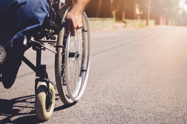 istock young disabled man in wheelchair walking park 1173400311
