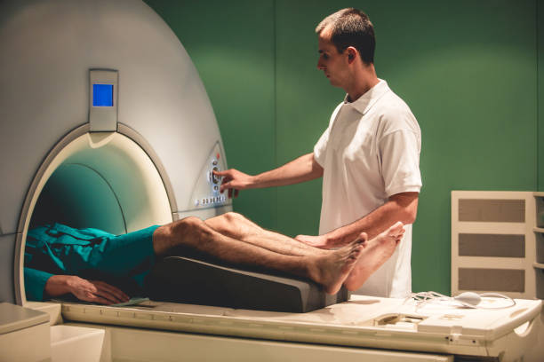 MRI scan in progress Medical technician doing an MRI scan on a patient. male nurse male healthcare and medicine technician stock pictures, royalty-free photos & images