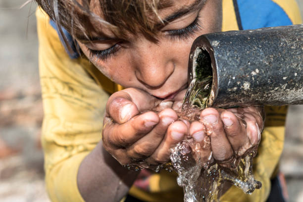 a young thirsty boy is drinking clean and sweet water