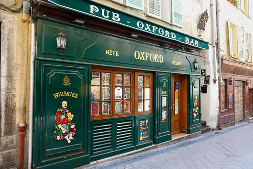 Nice, France - September 19, 2018: On a narrow street within the old town there is a pub, which now seems to be closed, but the green frontage is decorative, as if inviting to the inside. The city of Nice with its old town is full of historic buildings, churches and its narrow and shady streets allow you to feel the spirit of Old Nice. Contemporary architecture also emphasizes the modern character of the city. Nice is one of the most populated urban areas in France and the city is located on the French Riviera. Nice is the second largest city in the Provence-Alpes-Cote d'Azur region, and its location on the southeastern coast of France on the Mediterranean makes this place one of the most visited by tourists from all over the world.