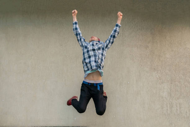 istock young man jumping high, winning or success gesture sign 1173412603