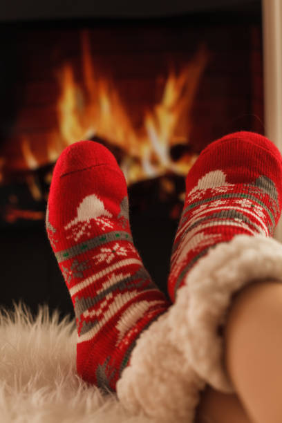 Christmas wool socks in front of fireplace A pair of feet in woolen Christmas socks are resting in front of a cozy fire. heat home interior comfortable human foot stock pictures, royalty-free photos & images