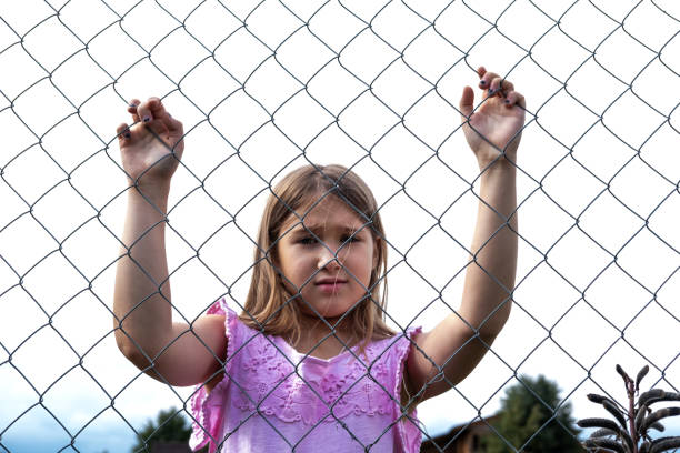 istock Sad girl behind metal wire mesh fence 1173417111