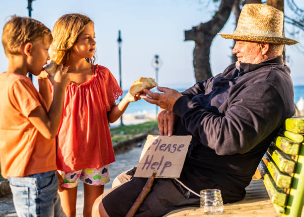 Boy and girl helping mature homeless men Homeless men asking for help and girl giving him a slice of bread begging currency beggar poverty stock pictures, royalty-free photos & images