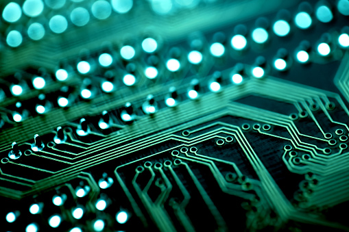 Close-up photo of an electronic circuit board in aquamarine tones. Shallow depth of field, beautiful bokeh.