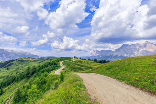 A picturesque rural road with cyclist riding mountain bike in Italian Dolomites, Alto Adige.